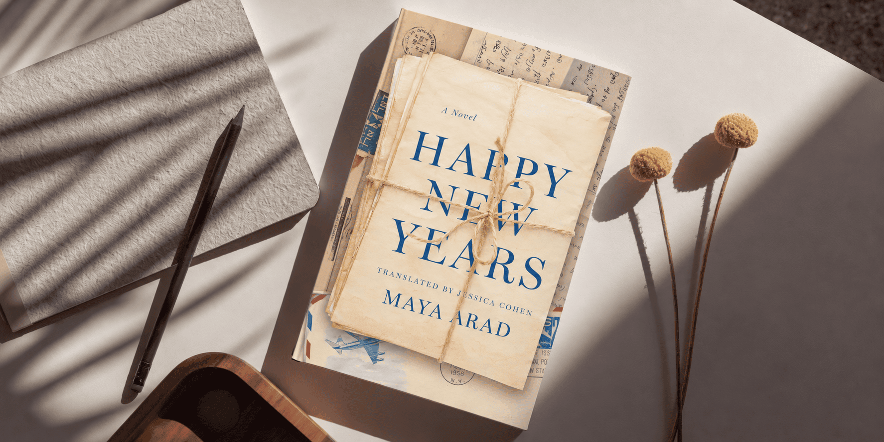 A copy of a book on a sunlit desk: Happy New Years by Maya Arad
